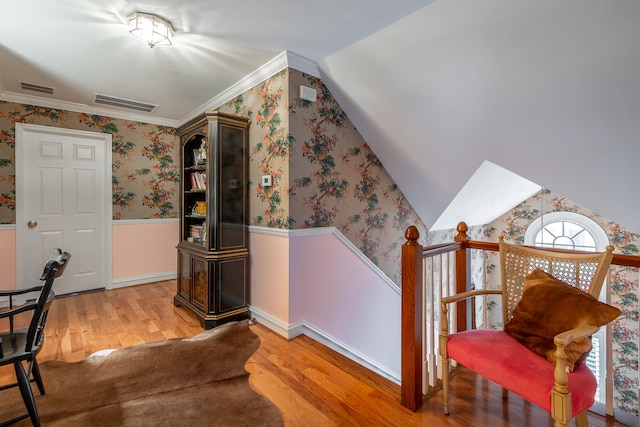 interior space with hardwood / wood-style floors, vaulted ceiling, and crown molding