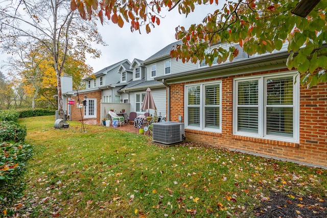 rear view of property featuring central AC unit, a lawn, and a patio