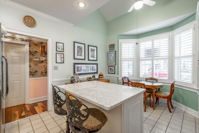 kitchen with ceiling fan, light tile patterned floors, vaulted ceiling, and ornamental molding