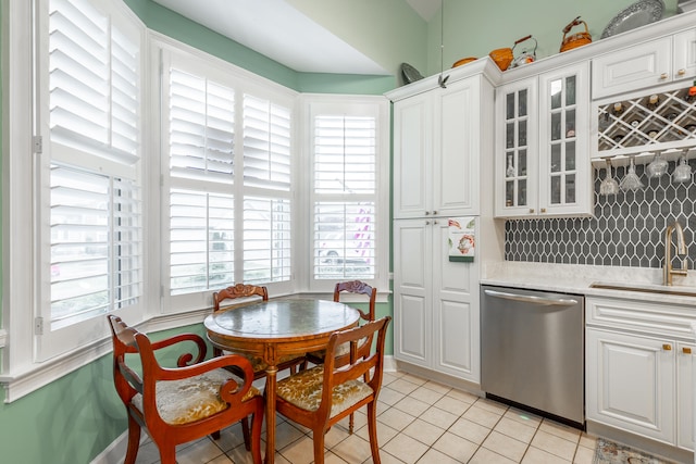 kitchen featuring dishwasher, sink, tasteful backsplash, light tile patterned floors, and white cabinetry