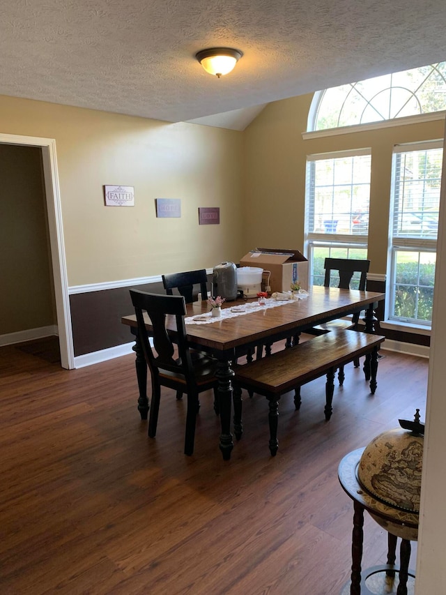 dining area featuring dark wood-type flooring and a textured ceiling