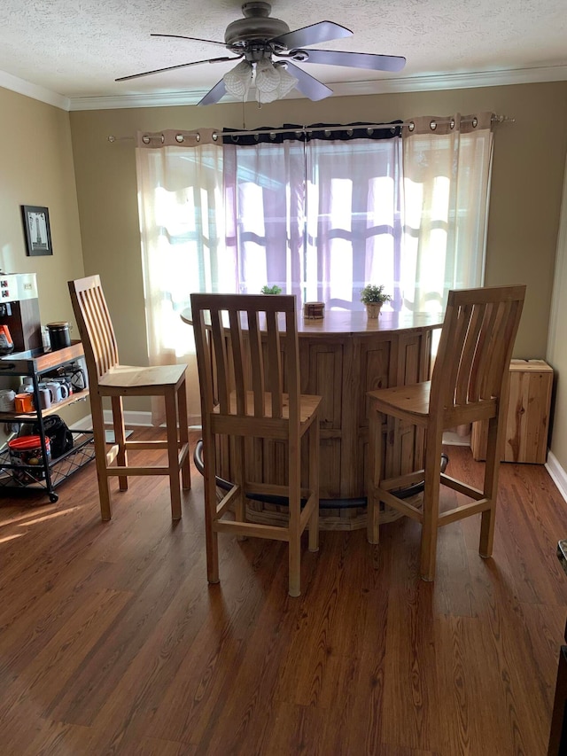 dining area with ceiling fan, wood-type flooring, crown molding, and a textured ceiling