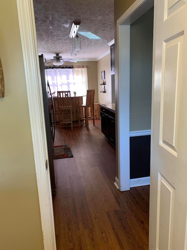 corridor with a textured ceiling, dark hardwood / wood-style floors, and crown molding