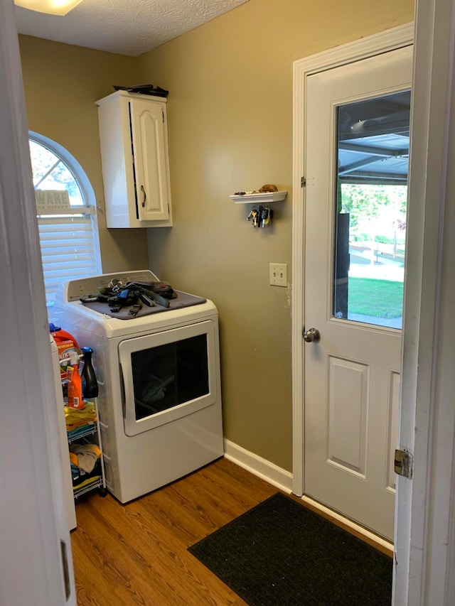 washroom with cabinets, light hardwood / wood-style flooring, washer / clothes dryer, and a textured ceiling