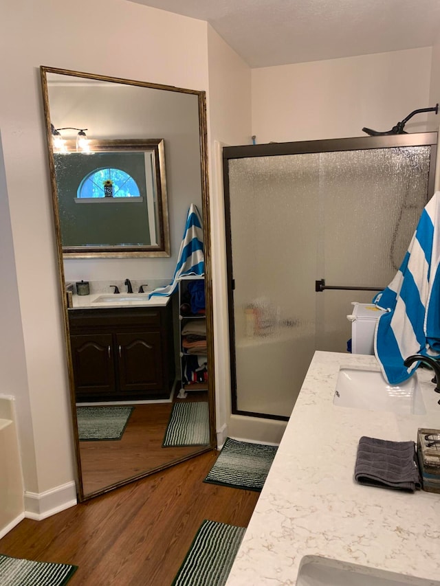 bathroom with hardwood / wood-style floors, vanity, and an enclosed shower