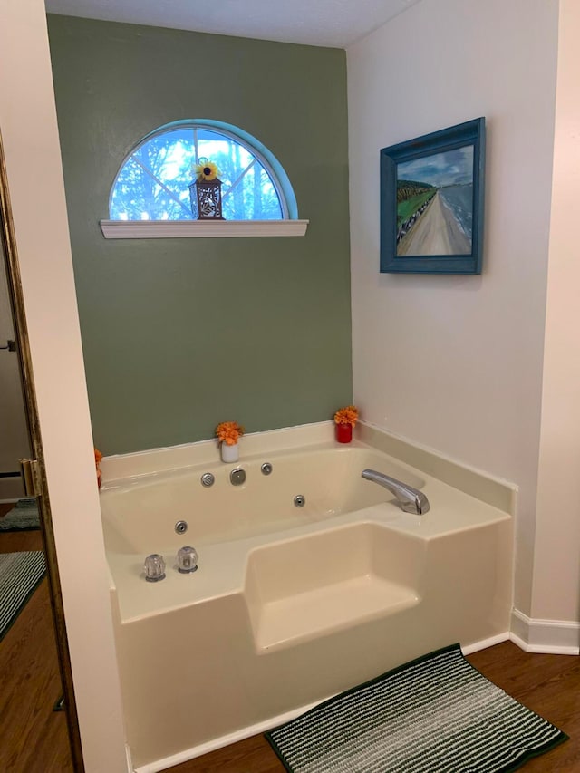 bathroom featuring hardwood / wood-style floors and a tub to relax in