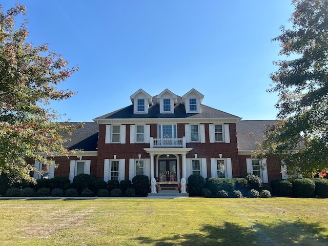 colonial-style house featuring a front yard and french doors