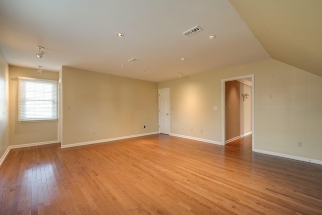 unfurnished room featuring lofted ceiling and light wood-type flooring