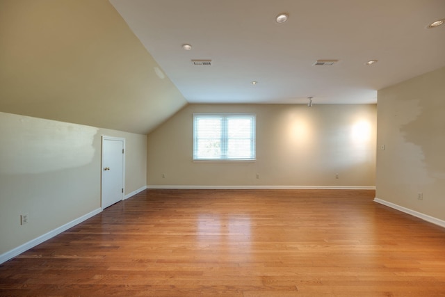 additional living space with vaulted ceiling and light wood-type flooring