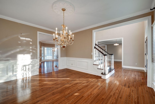 unfurnished dining area featuring hardwood / wood-style flooring, a notable chandelier, and crown molding