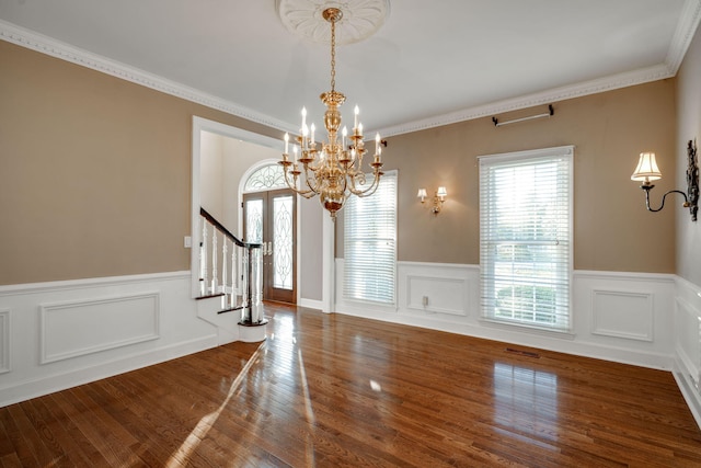 unfurnished dining area with crown molding, plenty of natural light, an inviting chandelier, and hardwood / wood-style flooring