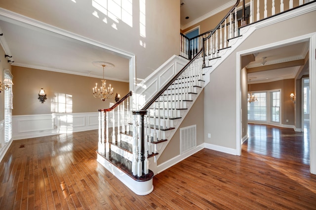 stairs featuring hardwood / wood-style flooring, crown molding, and an inviting chandelier