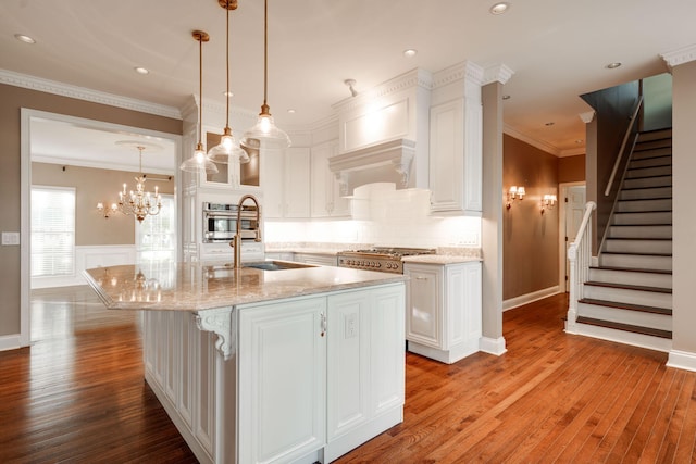 kitchen featuring white cabinetry, hanging light fixtures, and a kitchen island with sink