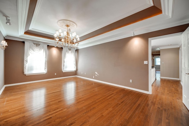 unfurnished room featuring a chandelier, a raised ceiling, and crown molding