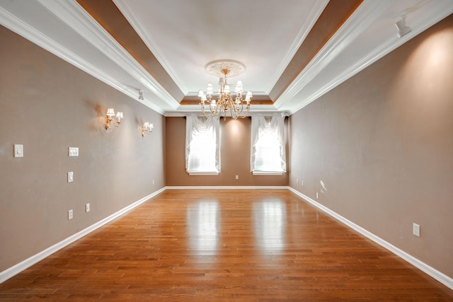 unfurnished room with a chandelier, hardwood / wood-style flooring, a raised ceiling, and ornamental molding