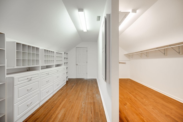 walk in closet featuring light wood-type flooring and vaulted ceiling