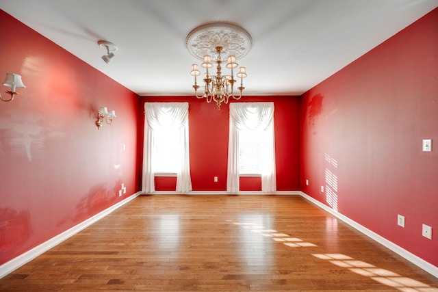 spare room featuring hardwood / wood-style floors and an inviting chandelier