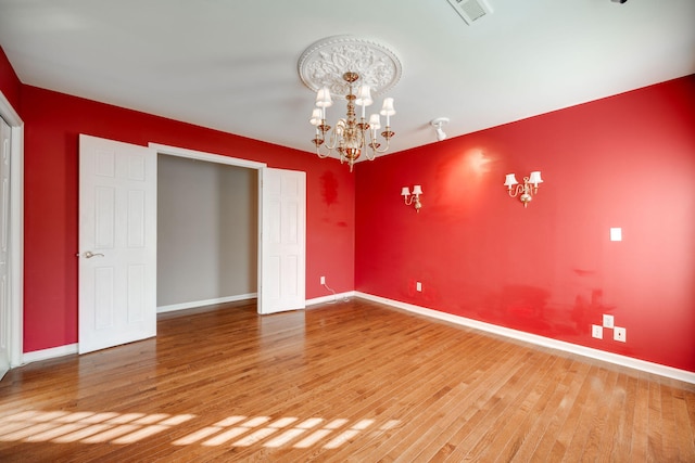 spare room featuring hardwood / wood-style flooring and a notable chandelier