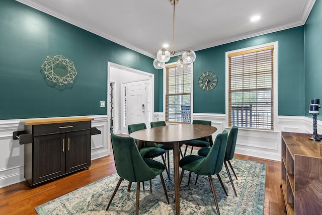 dining space with hardwood / wood-style floors, crown molding, and an inviting chandelier