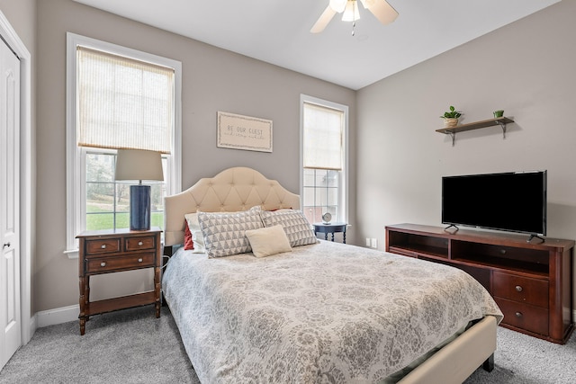 carpeted bedroom featuring ceiling fan, multiple windows, and a closet