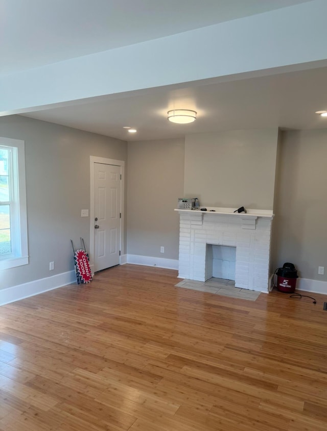 unfurnished living room with light hardwood / wood-style floors and a brick fireplace