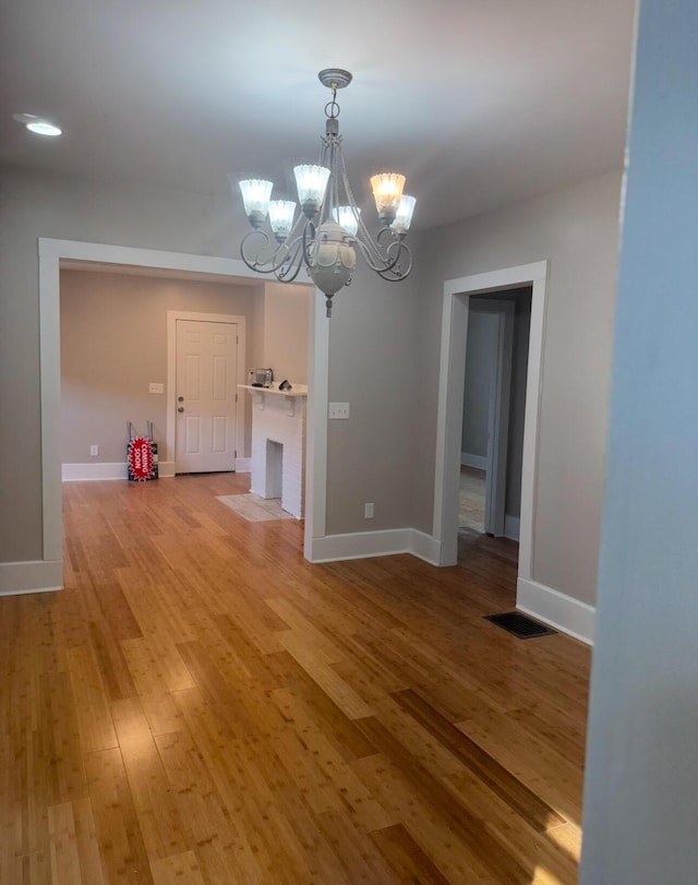 unfurnished dining area featuring a fireplace, hardwood / wood-style floors, and a chandelier