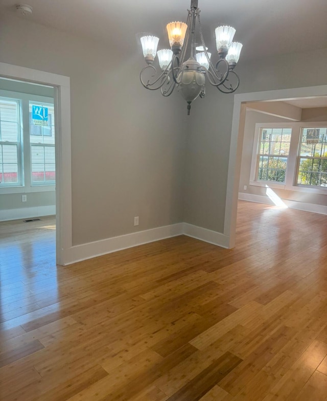 spare room with light hardwood / wood-style floors and an inviting chandelier