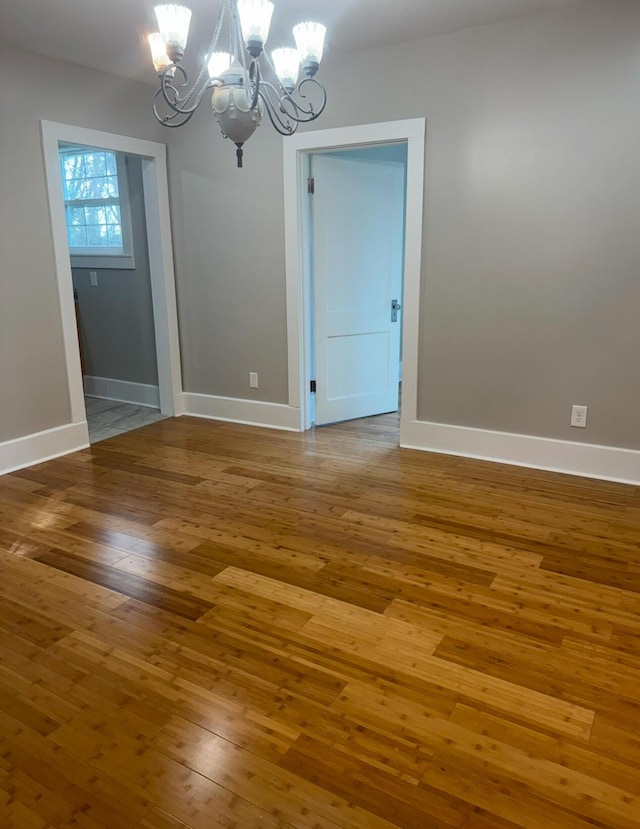 unfurnished dining area with hardwood / wood-style floors and a notable chandelier