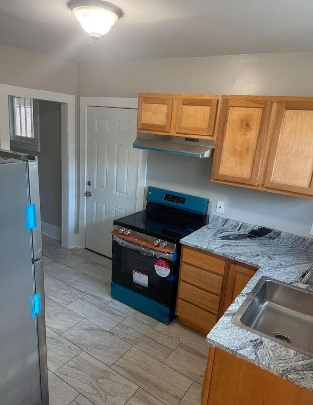 kitchen with stainless steel fridge, light stone counters, black electric range oven, and sink