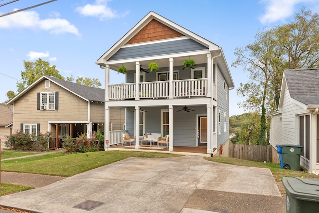 view of front facade with covered porch, a front yard, ceiling fan, and a balcony