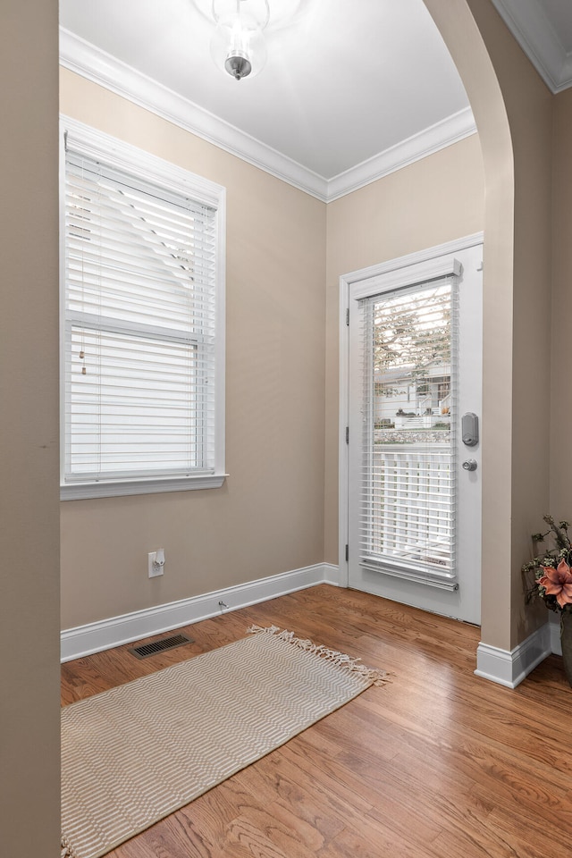 doorway to outside with hardwood / wood-style flooring and crown molding