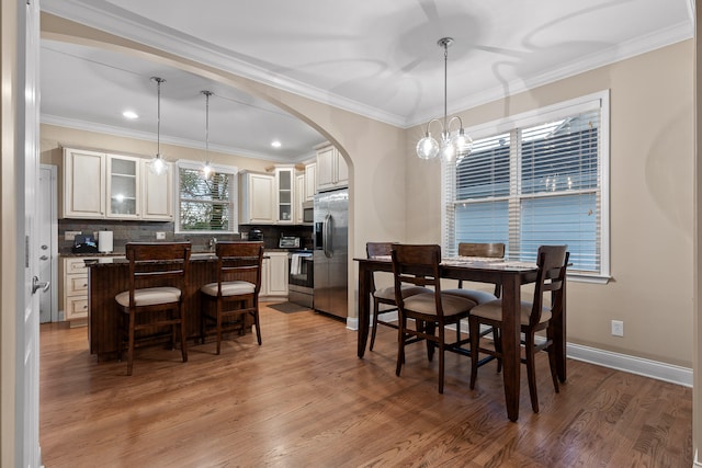 dining area with hardwood / wood-style floors, a chandelier, and crown molding