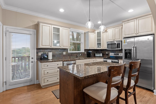 kitchen with a kitchen island, pendant lighting, a healthy amount of sunlight, and stainless steel appliances