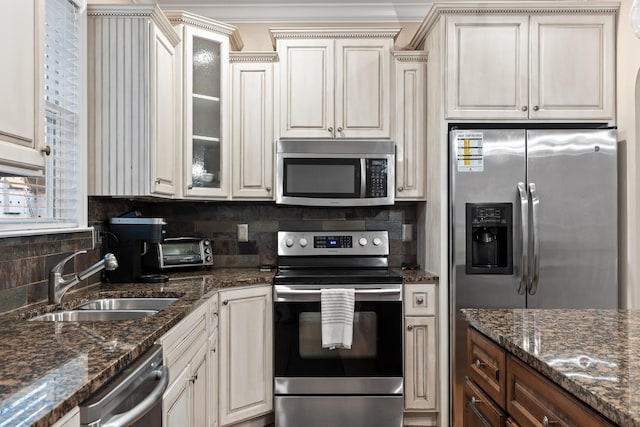 kitchen with stainless steel appliances, sink, tasteful backsplash, and dark stone countertops