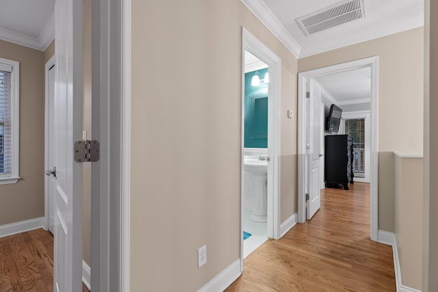 corridor with light wood-type flooring and ornamental molding