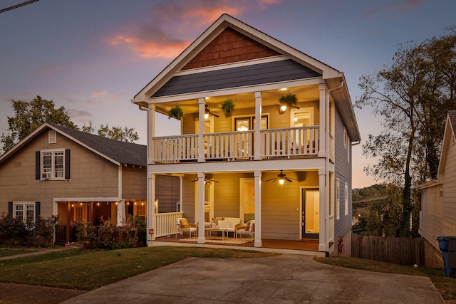 view of front of home with ceiling fan, a balcony, and a lawn