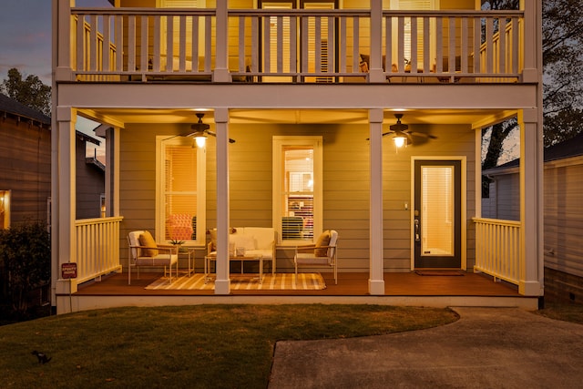 back house at dusk with ceiling fan and a balcony