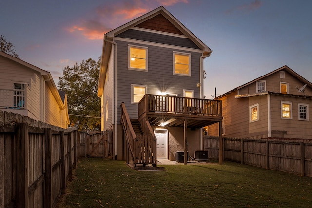 back house at dusk with central AC, a yard, and a wooden deck