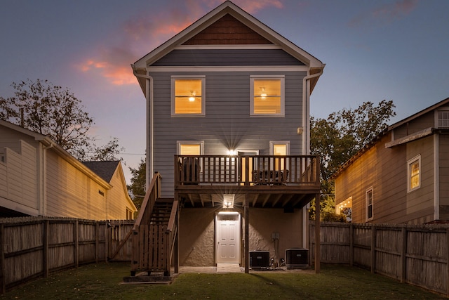 back house at dusk with a lawn and central AC