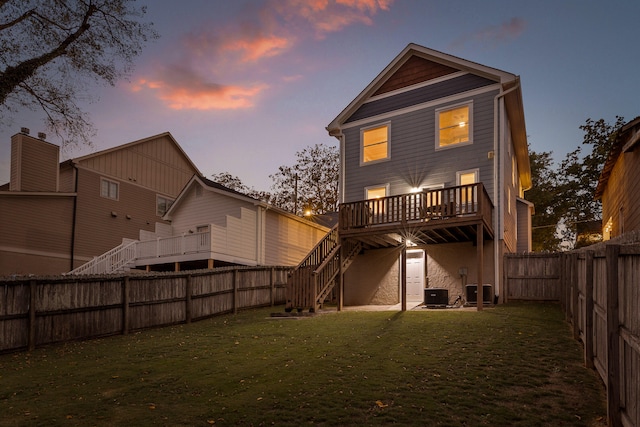 back house at dusk with a deck and a yard