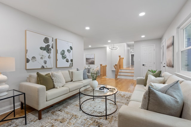 living room with a healthy amount of sunlight, light hardwood / wood-style floors, and a chandelier