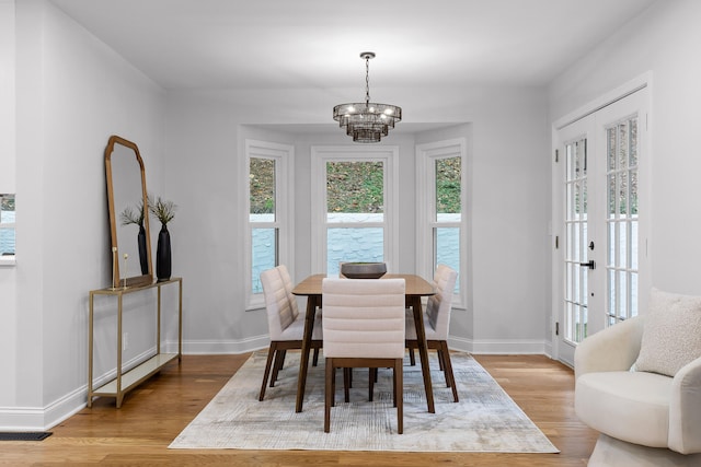 dining area with french doors, light hardwood / wood-style flooring, and an inviting chandelier