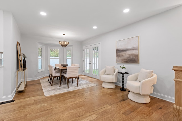 dining room featuring light wood-type flooring, a chandelier, and french doors