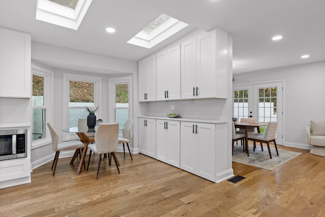 kitchen with light hardwood / wood-style floors, white cabinetry, backsplash, and lofted ceiling