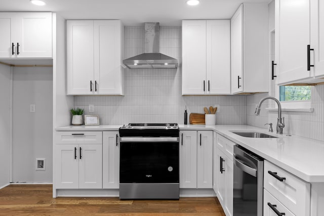 kitchen featuring stainless steel appliances, wall chimney exhaust hood, white cabinetry, and sink