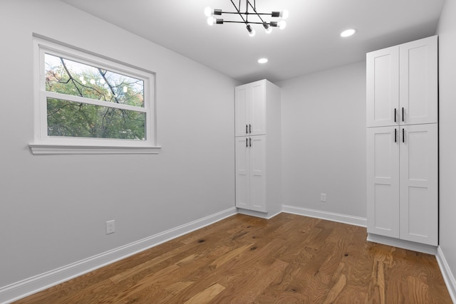 spare room with dark hardwood / wood-style flooring and an inviting chandelier