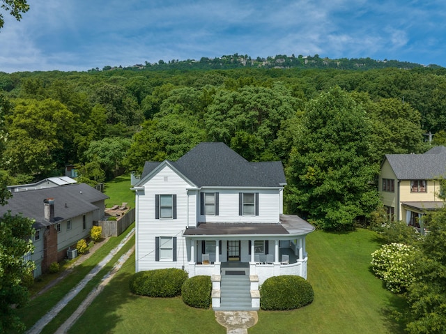 view of front facade featuring a front lawn, central air condition unit, and covered porch