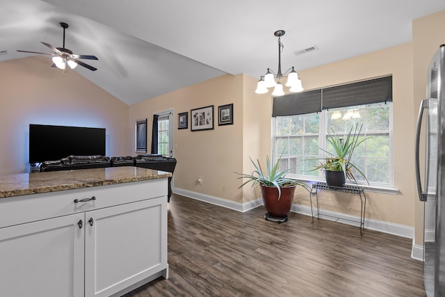 kitchen with white cabinetry, a wealth of natural light, dark stone counters, and vaulted ceiling