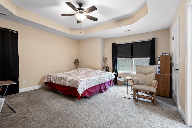 carpeted bedroom featuring ceiling fan and a tray ceiling