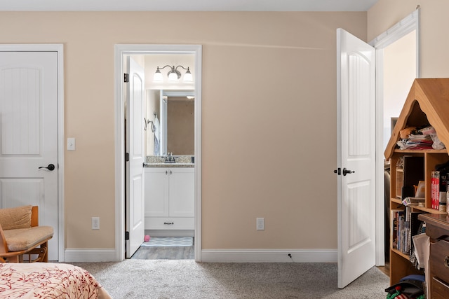 carpeted bedroom featuring ensuite bath and sink